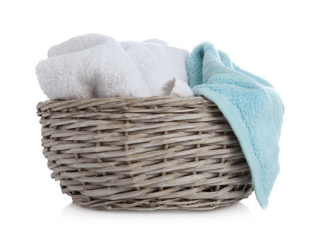 Wicker basket with towels isolated on whiteの写真素材