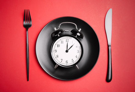 Alarm clock, plate and cutlery on red background, flat lay. Diet regimenの写真素材