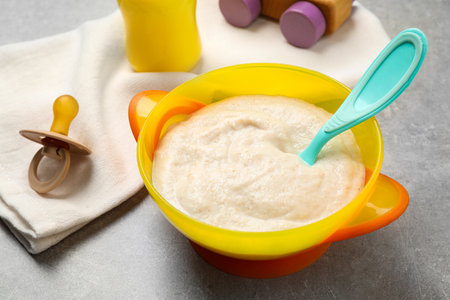 Healthy baby food in bowl on grey tableの写真素材