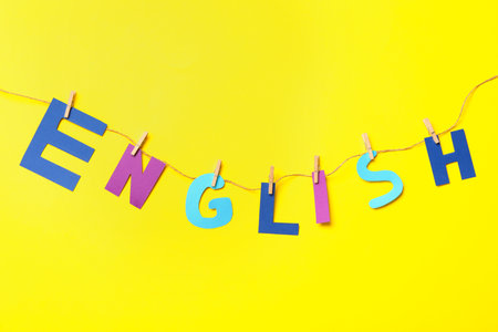 Thread with pinned word ENGLISH on yellow background, top viewの写真素材