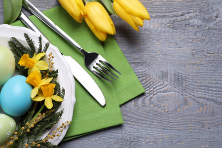 Festive Easter table setting with eggs on grey wooden background, flat lay. Space for textの写真素材