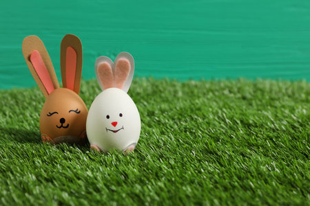 Easter eggs as cute bunnies on green grass, space for textの写真素材