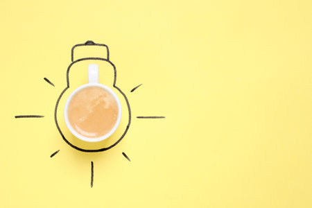Cup of coffee and drawn lightbulb on yellow background, top view. Space for textの写真素材