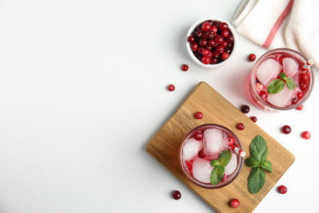 Tasty refreshing cranberry cocktail with mint on white table, flat lay. Space for textの写真素材