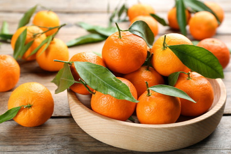 Fresh ripe tangerines with green leaves on wooden table, closeupの写真素材