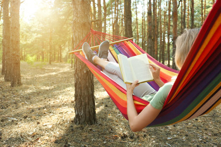Woman with book relaxing in hammock outdoors on summer dayの写真素材