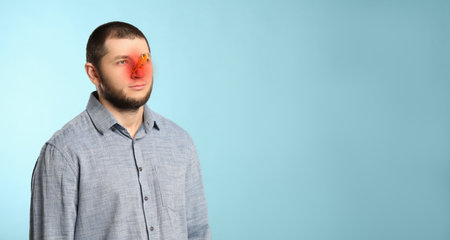Man with clothespin on light blue background, space for text. Runny nose conceptの写真素材