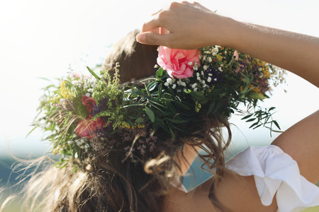 Young woman wearing wreath made of beautiful flowers outdoors on sunny day, closeupの写真素材