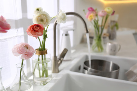 Light kitchen decorated with beautiful fresh ranunculus flowersの写真素材