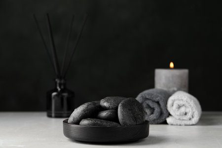 Spa stones with water drops on light gray marble table against black backgroundの写真素材
