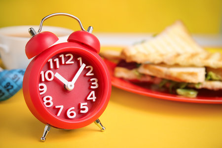 Alarm clock on yellow background, space for text. Diet regimeの写真素材