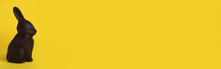 Dark chocolate bunny on yellow background, space for text. Easter celebrationの写真素材