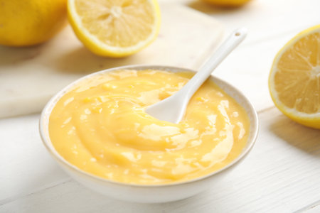 Delicious lemon curd in bowl on white wooden table, closeupの写真素材