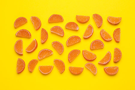 Delicious orange marmalade candies on yellow background, flat layの写真素材