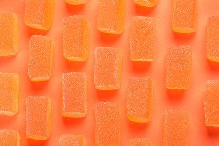 Tasty orange jelly candies on coral background, flat layの写真素材