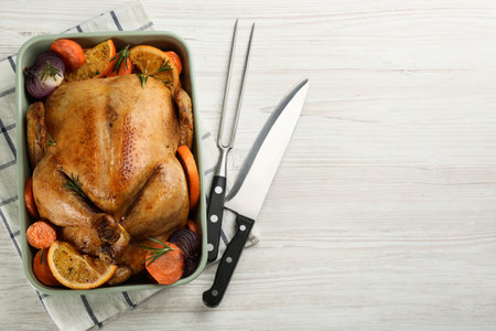 Delicious chicken with oranges and vegetables on white wooden table, flat lay. Space for textの写真素材
