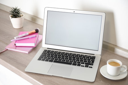 Modern laptop and cup of coffee on wooden table indoors. Space for designの写真素材