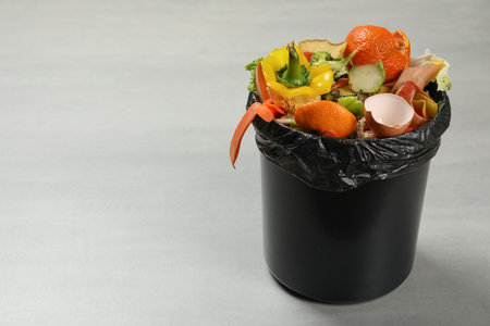 Trash bin with natural garbage on light background, space for text. Composting of organic wasteの写真素材