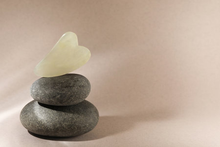 Jade gua sha tool and spa stones on brown background, space for textの写真素材