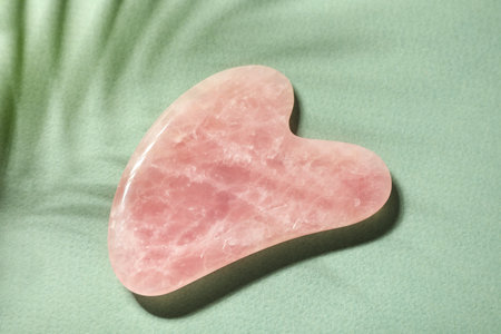 Rose quartz gua sha tool on green paper, top viewの写真素材