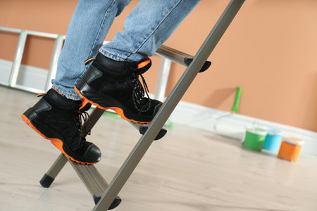 Person climbing ladder indoors, closeup on feetの写真素材