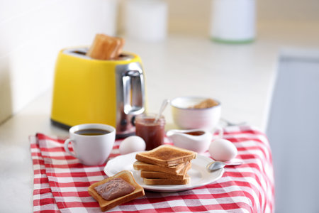 Modern toaster and delicious breakfast on table in kitchenの写真素材