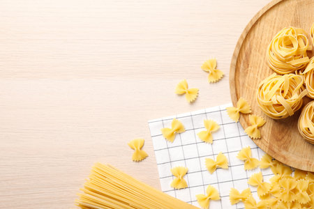 Different types of pasta on white wooden table, flat lay. Space for textの写真素材