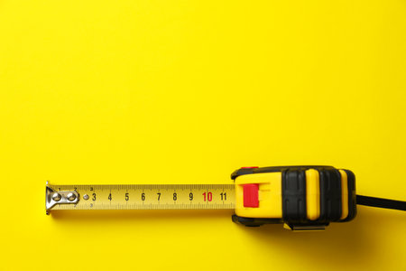 Tape measure on yellow background, top view. Space for textの写真素材