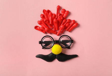 Funny face made with clown's accessories on pink background, flat layの写真素材