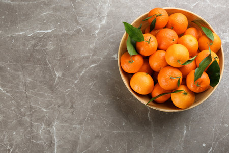 Fresh tangerines with green leaves on gray table, top view. Space for textの写真素材