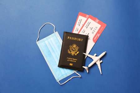 Flat lay composition with passport and protective mask on blue background. Travel during quarantineの写真素材