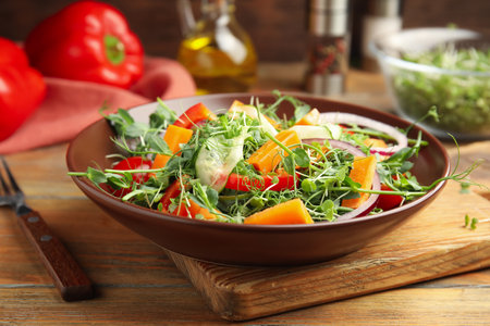 Delicious vegetable salad with microgreens served on wooden tableの写真素材