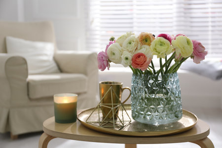 Beautiful ranunculus flowers in vase on wooden table indoors, space for text