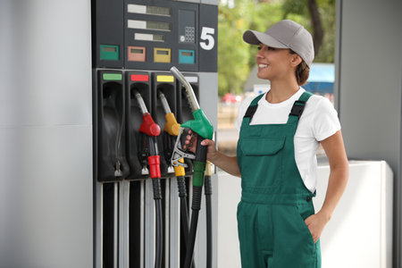 Young worker with fuel pump nozzle at modern gas stationの写真素材