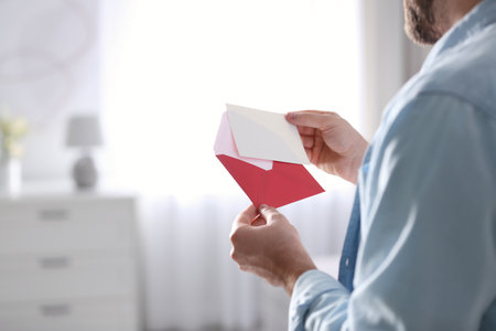 Man holding envelope with greeting card at home, closeupの写真素材
