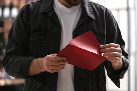 Man holding envelope with greeting card indoors, closeupの写真素材