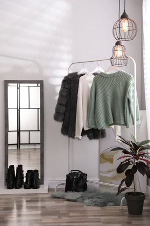 Stylish warm clothes on rack in dressing room interiorの写真素材