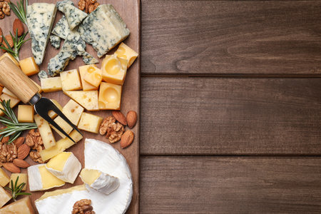 Cheese plate with rosemary and nuts on wooden table, top view. Space for textの写真素材