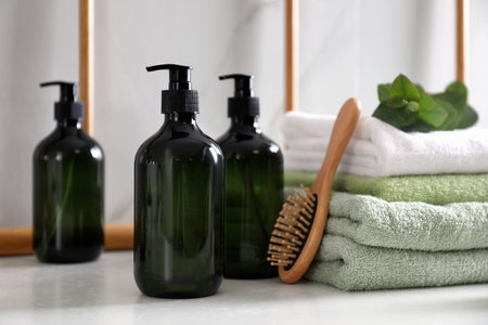 Soap dispensers, brush and towels on countertop in bathroomの写真素材
