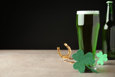 Green beer and St Patrick's Day decor on light gray table against black background. Space for textの写真素材