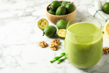 Fresh feijoa smoothie in glass on white marble table, closeup. Space for textの写真素材