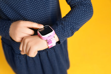 Little girl with smart watch on yellow background, closeupの写真素材