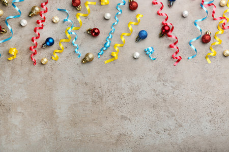 Shiny serpentine streamers and Christmas balls on gray background, flat lay. Space for textの写真素材