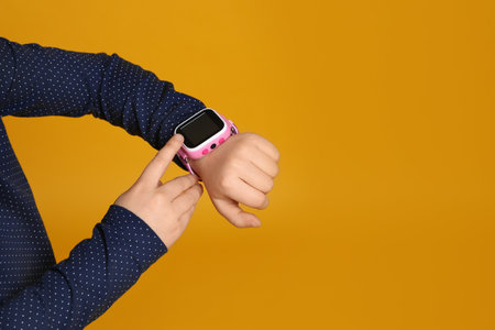 Little girl with smart watch on yellow background, closeup. Space for textの写真素材