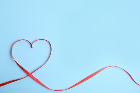 Heart made of red ribbon on light blue background, top view with space for text. Valentine's day celebrationの写真素材