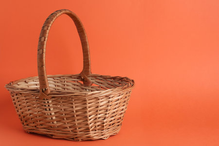 Empty wicker basket on coral background, space for text. easter itemの写真素材