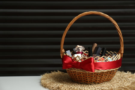 Wicker gift basket with cosmetic products on white table against dark background. Space for textの写真素材