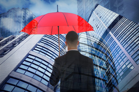 Businessman with umbrella in city center. insurance conceptの写真素材