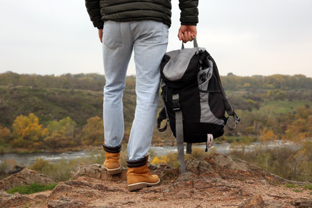 Man wearing stylish hiking boots with backpack on steep cliff, closeupの写真素材