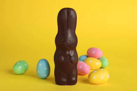 Chocolate Easter bunny and dyed eggs on yellow backgroundの写真素材